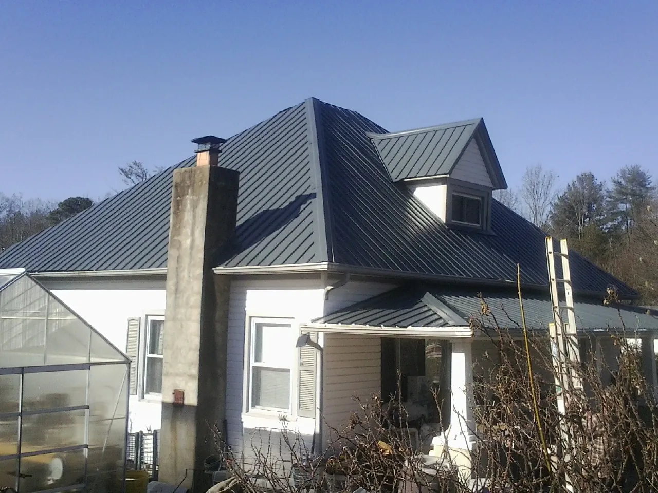 Dark blue standing seam metal roof on a white farmhouse with dormer — Slate & Tile Roof Repair by Roofing Brothers in Line Lexington