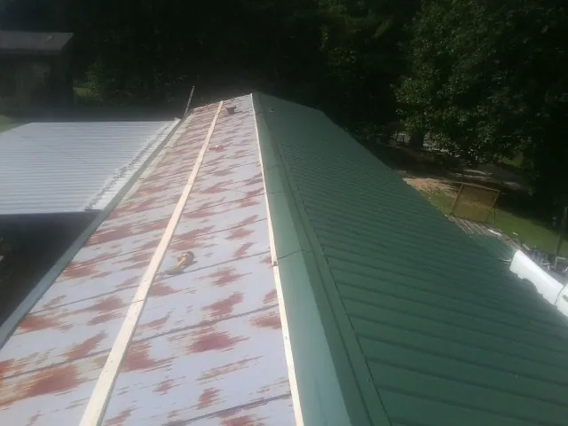 Old rusted panels beside newly installed green metal roofing — Wind Damage Roof Repair by Roofing Brothers in Line Lexington