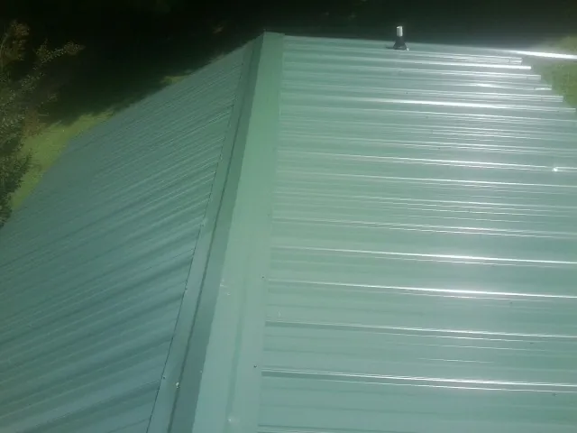 New green metal panels meeting at the ridge of a roof — Flat Roof Repair work by our crew in Line Lexington