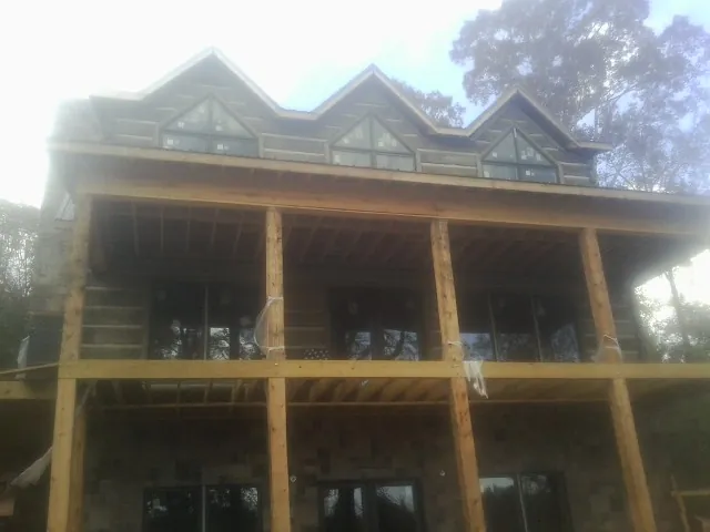 Dormers and porch framing on a large log home under construction — Roof Coating work by our crew in Line Lexington