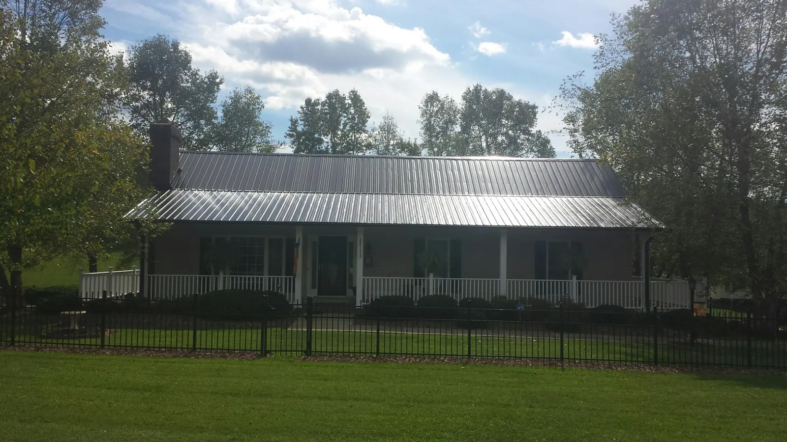 Gray metal roof on a brick ranch with a full width front porch — Gutter Guard Installation work by our crew in Line Lexington