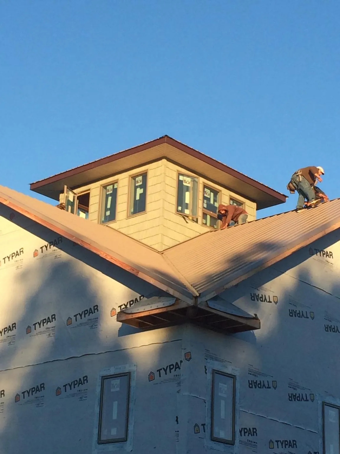 Roofers working around a rooftop cupola on a new metal roof at sunset — Roof Waterproofing in Line Lexington by Roofing Brothers